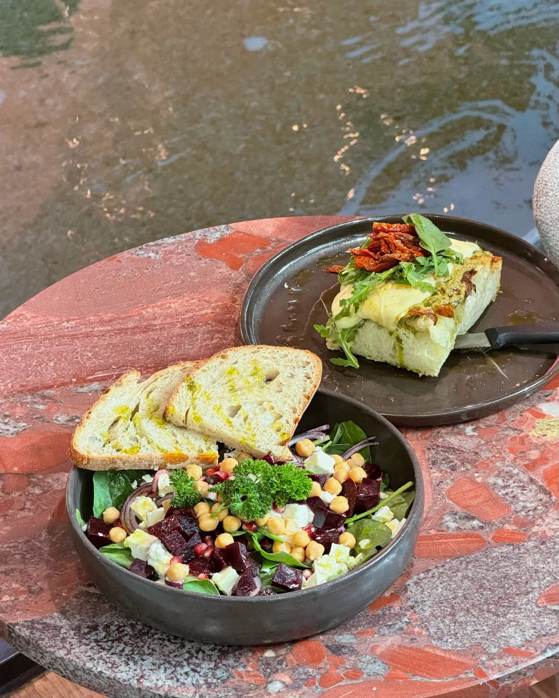 Bowl mit Roter Rübe, Kichererbsen und Feta, dazu Focaccia auf dem roten Steintisch